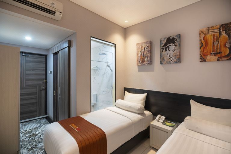 a modern hotel room with a bed , nightstands , and a glass shower door , along with two paintings on the wall at Front One Boutique Karawang