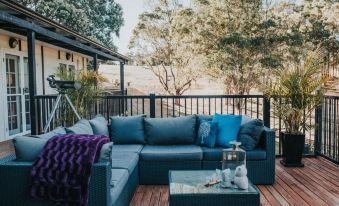 a cozy outdoor living area with a couch , coffee table , and potted plants on a wooden deck at Nannup Hideaway