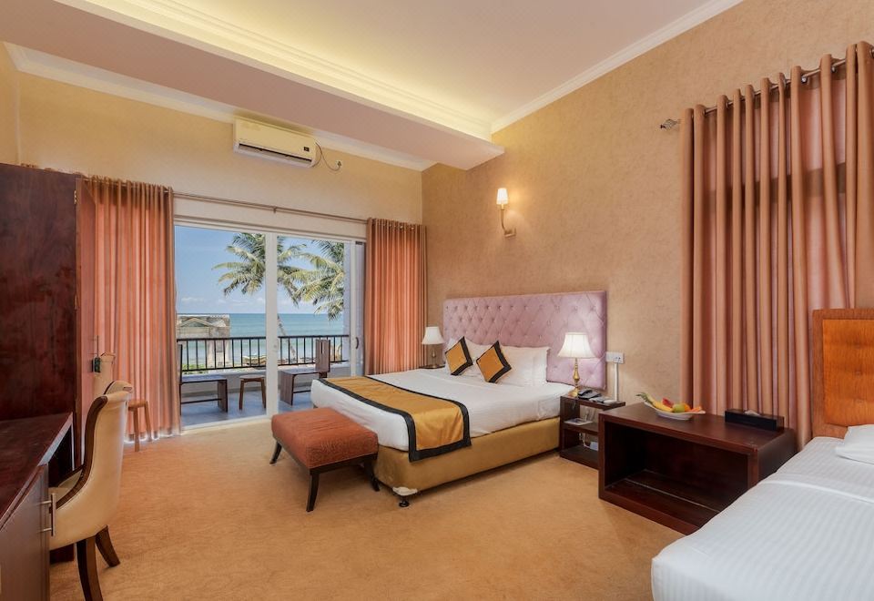 The bedroom features a double bed and a balcony with a view of the sea during sunset or sunrise at Seagate Hotel