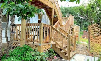 a wooden deck with stairs leading up to a house , surrounded by greenery and trees at Micosta Leisure Inn