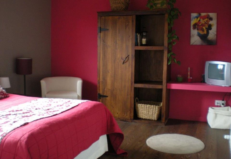 a cozy bedroom with a bed , nightstands , and a wooden wardrobe , all set against pink walls at Punto y Aparte