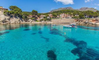 a beautiful blue sea with clear water , surrounded by lush green hills and a village on the other side at Mon Port Hotel & Spa