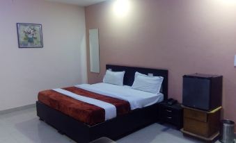 a large bed with a red and white blanket is in a room with a pink wall at Hotel International