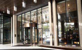 an entrance to a building with a glass door and a striped floor , surrounded by trees at The Riverside Hotel