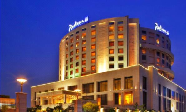a large hotel with a hotel sign on the front , surrounded by trees and lit up at night at Radisson Blu New Delhi Dwarka