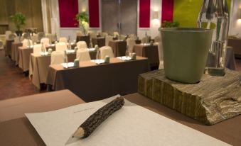 a pen is placed on a piece of paper in front of a table with empty chairs and a large plant at Six Senses Krabey Island