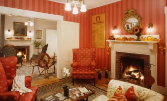 a cozy living room with a fireplace , red and white striped walls , and a red chair at Sunset Hill House