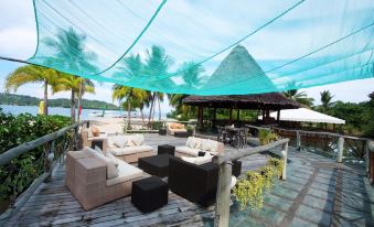 a cozy outdoor seating area under a blue tarp , surrounded by palm trees and overlooking the ocean at Badian Island Wellness Resort