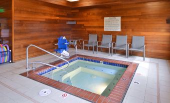 a hot tub with a red tile border and blue jets is surrounded by chairs at Hampton Inn Portland East