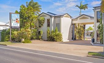 a white building with a glass door is surrounded by palm trees and bushes on a street at Coral Cay Resort