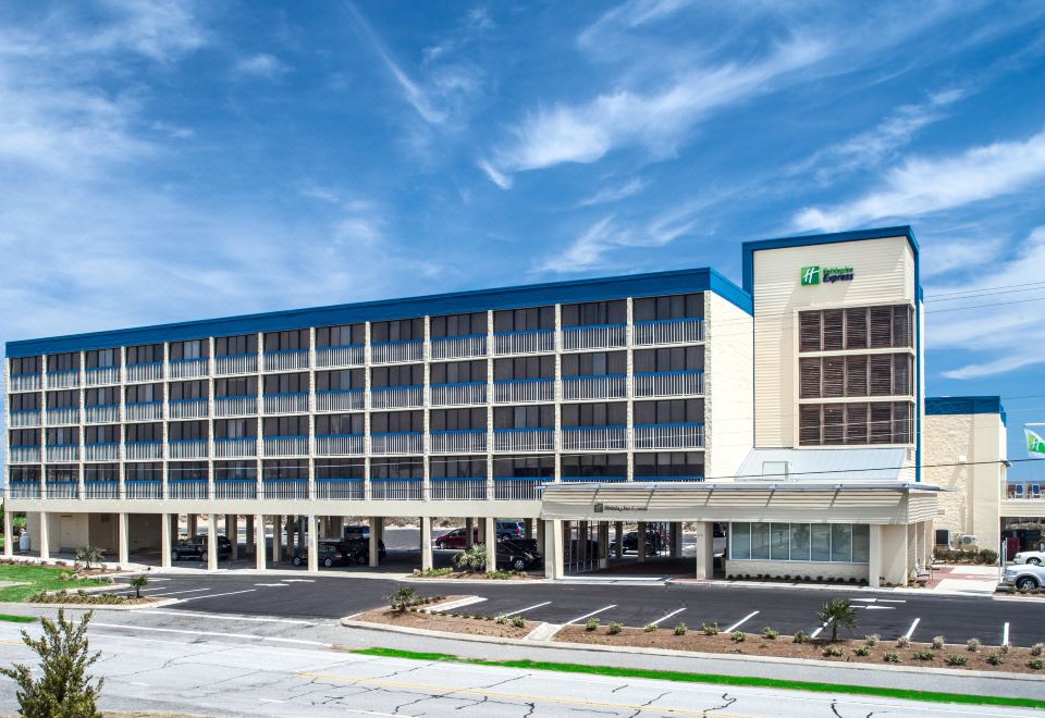 a large , modern hotel with a blue and white color scheme , situated in a parking lot at Holiday Inn Express Nags Head Oceanfront