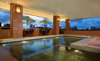 an indoor swimming pool with umbrellas and tables , situated on the rooftop of a building at Best Western Plus Makassar Beach