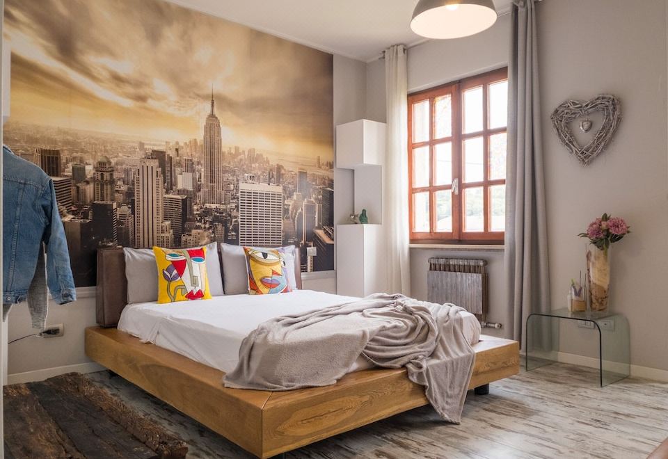 a large bed with wooden headboard and white sheets is in a room with a city mural on the wall at Nest