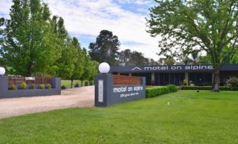 "a grassy area with a building in the background and a sign that reads "" motel on alpine .""." at Myrtleford Motel on Alpine