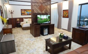 a living room with a large flat - screen tv mounted on the wall , a couch , and a dining table at Westlake Hotel & Resort Vinh Phuc
