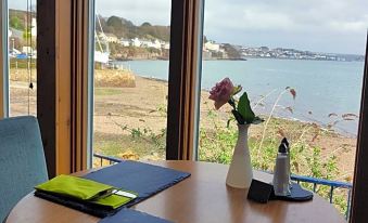 a dining table with blue and yellow place mats , a vase of flowers , and a view of the ocean at Ferry House Inn