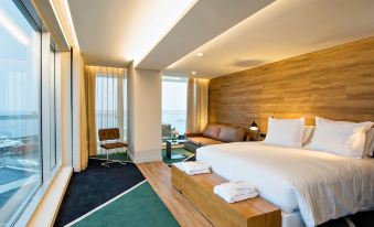 a large bed with white linens is in a room with a green rug , wooden walls , and a sliding glass door leading to a balcony at Octant Ponta Delgada