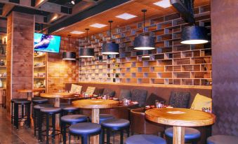 a modern restaurant interior with wooden tables , blue stools , and pendant lights , as well as a tv screen on the wall at DoubleTree by Hilton Reading
