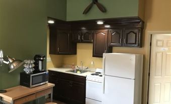 a kitchen with dark wood cabinets , a white refrigerator , and a stove top oven under a wooden cabinet at Lofts on Main