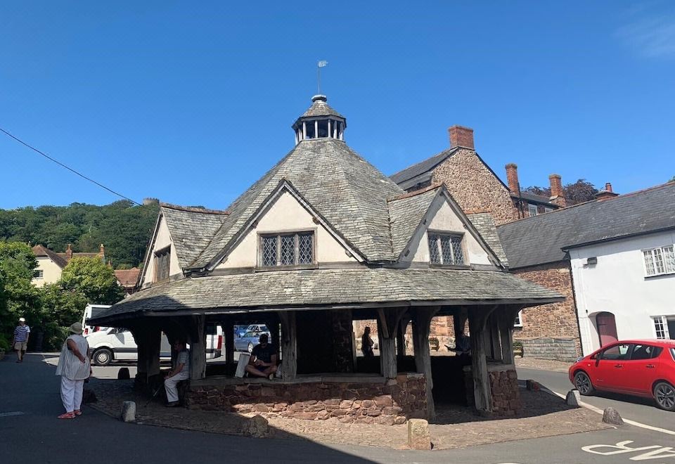 a small wooden gazebo in front of a brick building , surrounded by a courtyard with a cobblestone walkway at The Carew Arms