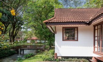 a white house with a red - tiled roof is surrounded by greenery and has a small pond in front of it at Supalai Pasak Resort Hotel and Spa