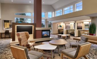 a large , well - lit room with multiple chairs and couches arranged around a dining table , creating a cozy atmosphere at Residence Inn Greenville