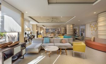 a modern hotel lobby with a large couch , chairs , and a coffee table in the center at Abora Continental by Lopesan Hotels