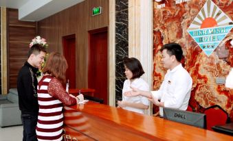 a man and a woman standing at the front desk of a hotel , greeting each other at Binh Minh Hotel