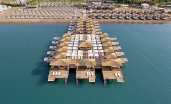 aerial view of a resort with multiple huts on stilts over a body of water at Titanic Deluxe Lara