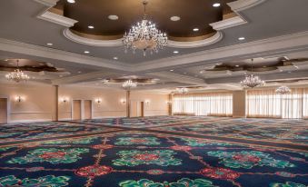 a large , empty banquet hall with multiple chandeliers and a carpeted floor , as well as windows and a balcony at St. Kitts Marriott Resort & the Royal Beach Casino