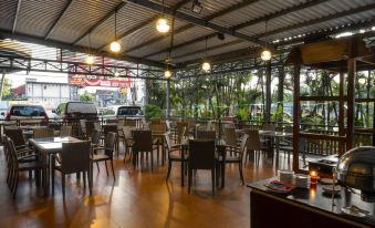 a large , open - air restaurant with wooden floors and chairs , set in a tropical setting with palm trees at Solaris Hotel Malang