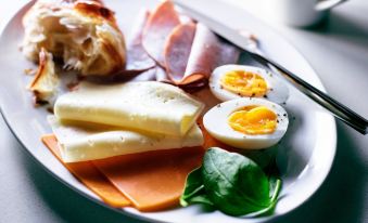 a plate filled with various types of food , including ham , cheese , and an egg , placed on a dining table at SpringHill Suites Florence