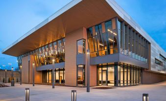 a modern building with wooden exterior and large glass windows is shown at dusk at Delta Hotels Muskegon Convention Center