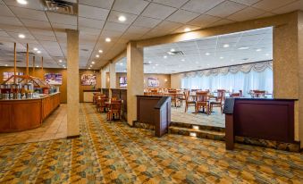 a large , empty restaurant with multiple dining tables and chairs , as well as a bar area at Best Western Plus Chicago Hillside