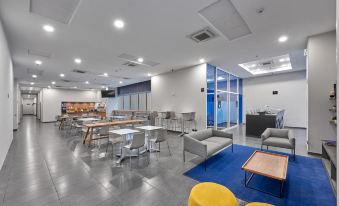a modern , open - concept office space with a bar and multiple seating areas , including couches , chairs , and tables at City Express by Marriott Cdmx la Villa