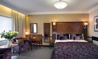 a hotel room with a large bed , wooden furniture , and a window with curtains , as well as a desk and chair at Quorn Country Hotel