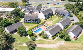 aerial view of a residential area with multiple buildings and a swimming pool in the center , surrounded by green grass and trees at Camden Valley Inn