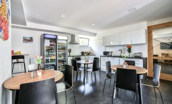 a modern kitchen with white cabinets , a dining area with black tables and chairs , and an open refrigerator at Vincent