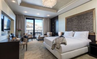a large bed with white linens is in a room with chairs and a chandelier at Shahdag Hotel & Spa