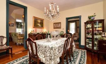 a dining room with a large table covered in a white tablecloth , surrounded by chairs at Colonial Beach Plaza Bed & Breakfast