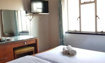 a hotel room with a bed , tv , and window , decorated with towels on the bed at Plaza Hotel