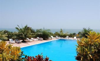 a large , blue swimming pool surrounded by lush greenery and a view of the ocean at Hotel Maya