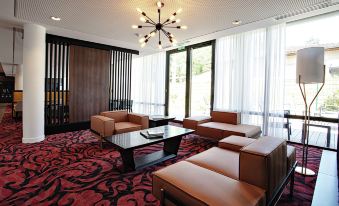 a modern living room with a red and black carpeted floor , brown leather couches , and a wooden coffee table at Hampton by Hilton Toulouse Airport