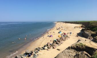 a sandy beach with numerous people enjoying their time in the water and on the sand at Primrose Cottage