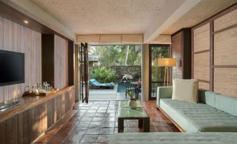 a living room with a couch , coffee table , and sliding glass doors leading to a pool area at Jeeva Klui Resort