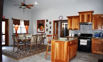 a well - equipped kitchen with wooden cabinets , a dining table , and a stove , as well as a living room area at Lucina's