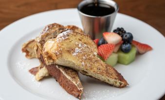 a white plate with a delicious breakfast consisting of french toast , berries , and a cup of coffee at Four Points by Sheraton - San Francisco Bay Bridge