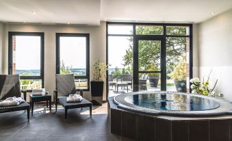 a modern living room with large windows , a hot tub , and various furniture items , such as chairs and tables at Hôtel du Golf