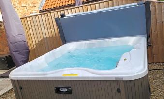 a large hot tub with a silver cover is situated outside next to a wooden fence at The Blue Bell Inn