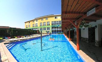 a large swimming pool with a wooden walkway and several people in it , surrounded by a building at Hotel Seneca